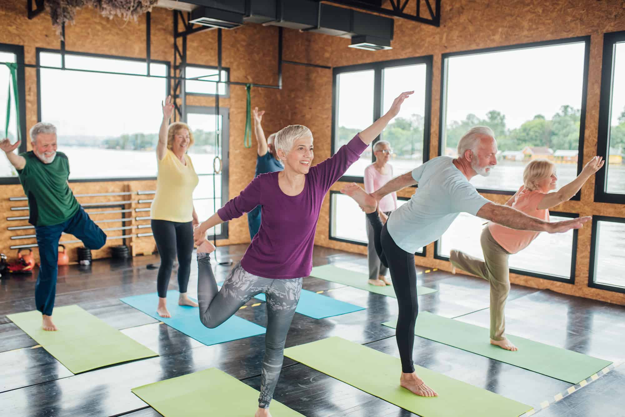 Residents practicing yoga at Cadence Creek at Gosling 55 and over apartments, featuring yoga mats and large windows.